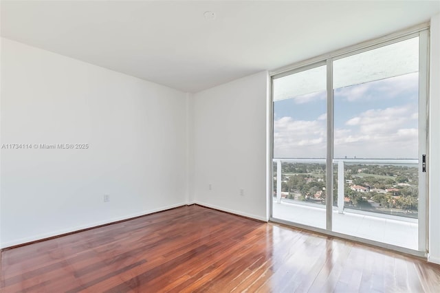 unfurnished room with hardwood / wood-style floors and expansive windows