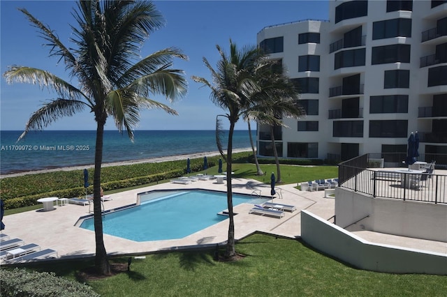 view of pool featuring a water view, a yard, a view of the beach, and a patio