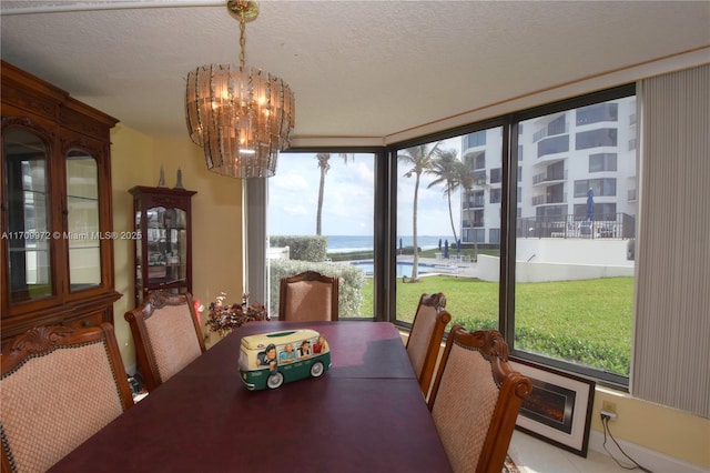 dining space featuring an inviting chandelier, a textured ceiling, and a water view