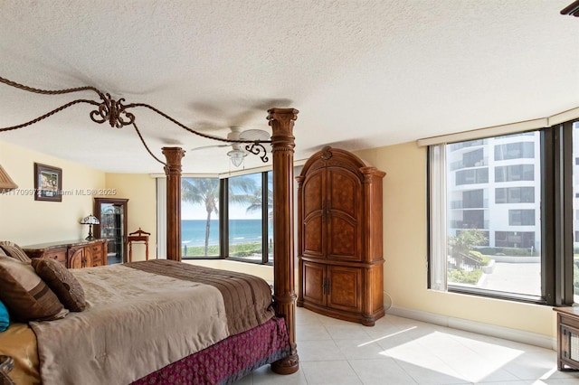 tiled bedroom with a water view and a textured ceiling