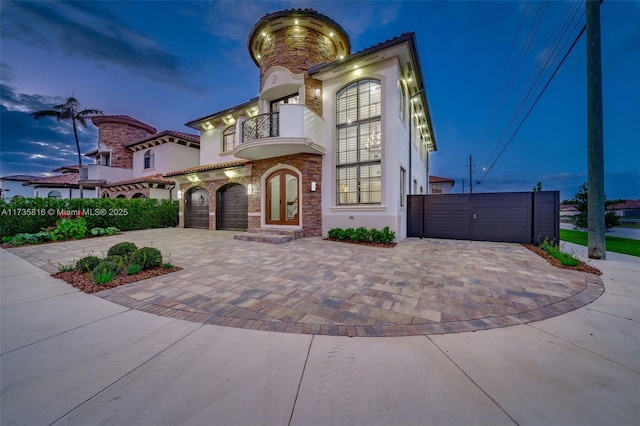 mediterranean / spanish-style home with a garage, french doors, and a balcony