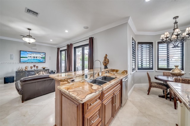 kitchen featuring pendant lighting, sink, light stone countertops, and an island with sink