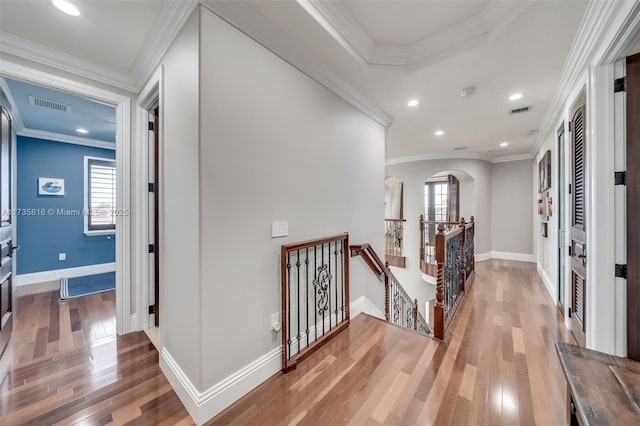 hallway with ornamental molding, a healthy amount of sunlight, and hardwood / wood-style floors