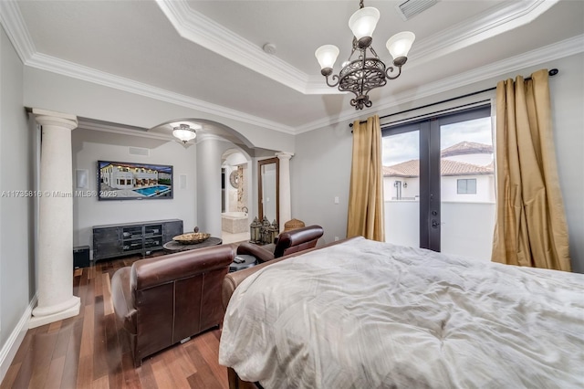 bedroom featuring ornate columns, hardwood / wood-style floors, ornamental molding, a tray ceiling, and french doors