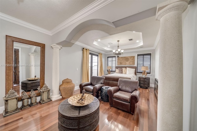 bedroom with hardwood / wood-style flooring, access to exterior, ornamental molding, a raised ceiling, and ornate columns