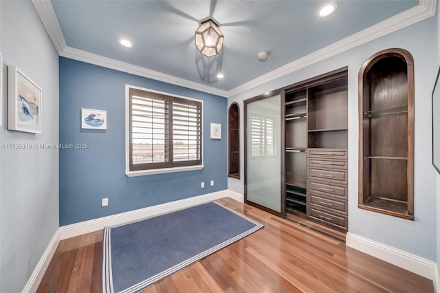 interior space with crown molding, wood-type flooring, and a closet