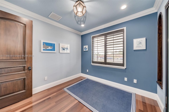 foyer entrance with ornamental molding and hardwood / wood-style floors