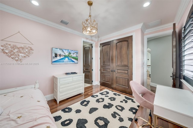 bedroom featuring hardwood / wood-style flooring, ornamental molding, and a notable chandelier