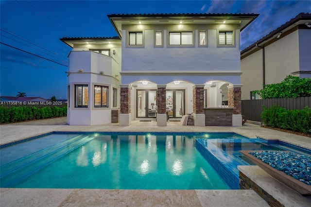 rear view of house featuring exterior bar, a patio area, and a pool with hot tub