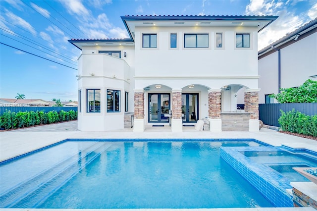 back of house featuring a swimming pool with hot tub and a patio