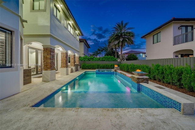 pool at dusk featuring a patio