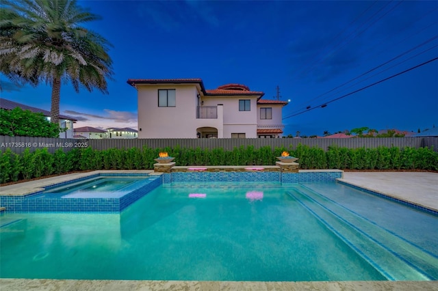 pool at dusk featuring an in ground hot tub