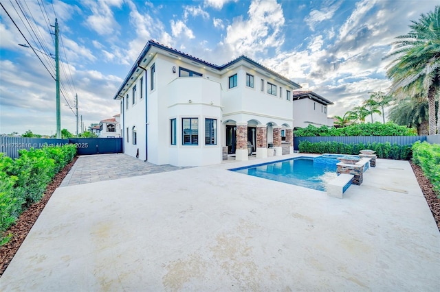 rear view of property featuring a swimming pool with hot tub and a patio