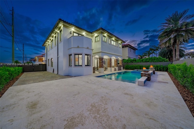 back house at dusk with a swimming pool with hot tub and a patio