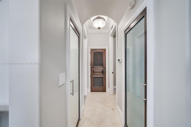 hallway with ornamental molding and a textured ceiling