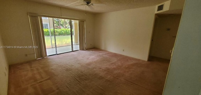 carpeted empty room featuring ceiling fan, visible vents, and a textured ceiling