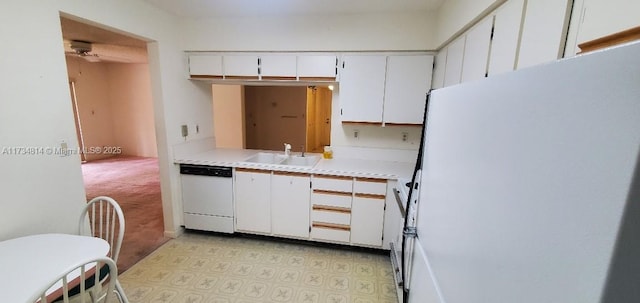 kitchen featuring light countertops, freestanding refrigerator, white cabinets, white dishwasher, and a sink