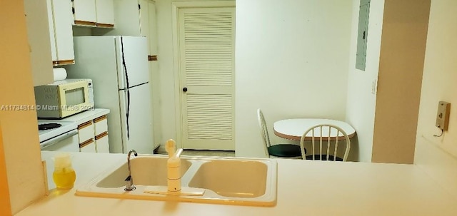 kitchen with white appliances, white cabinetry, light countertops, and a sink