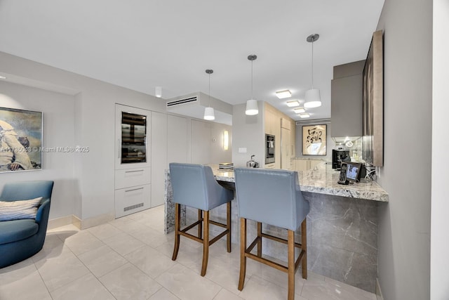 kitchen with light stone counters, decorative light fixtures, a breakfast bar area, and kitchen peninsula