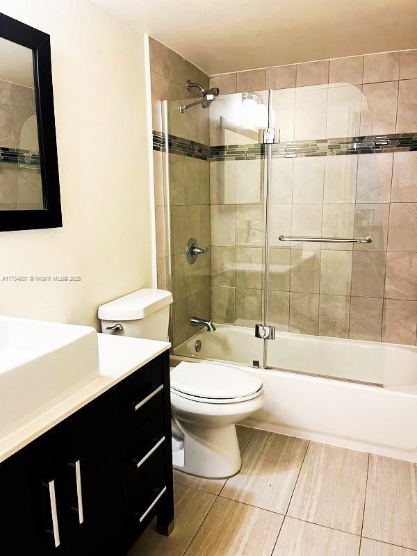 full bathroom with vanity, bath / shower combo with glass door, and toilet