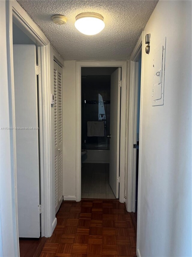 hall featuring dark parquet flooring and a textured ceiling