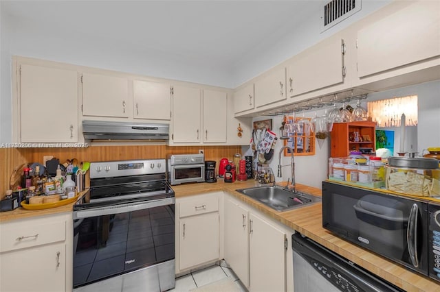 kitchen with appliances with stainless steel finishes, sink, light tile patterned floors, and white cabinets