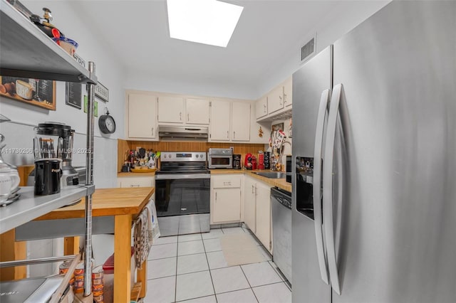 1666 W Ave Unit 207, Miami Beach, FL 33139 - kitchen with appliances with stainless steel finishes, under cabinet range hood, light countertops, and light tile patterned flooring