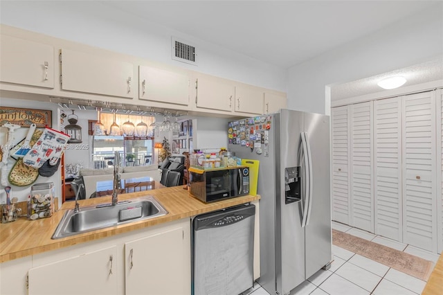 1666 W Ave Unit 207, Miami Beach, FL 33139 - kitchen featuring stainless steel appliances, light countertops, light tile patterned flooring, and white cabinetry