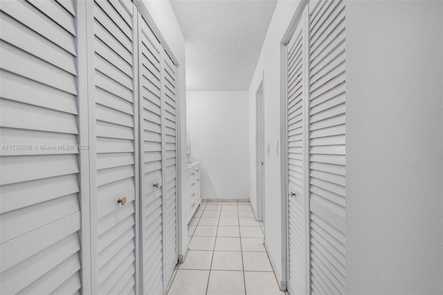 corridor with light tile patterned floors and a textured ceiling