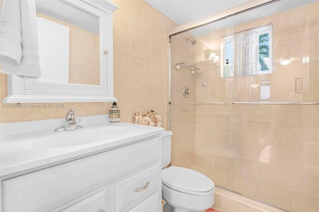 bathroom featuring vanity, toilet, tile walls, and walk in shower