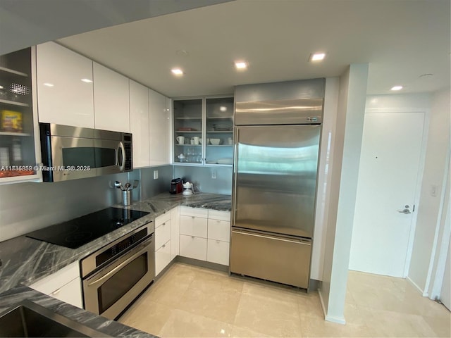 kitchen featuring dark stone countertops, white cabinets, and appliances with stainless steel finishes