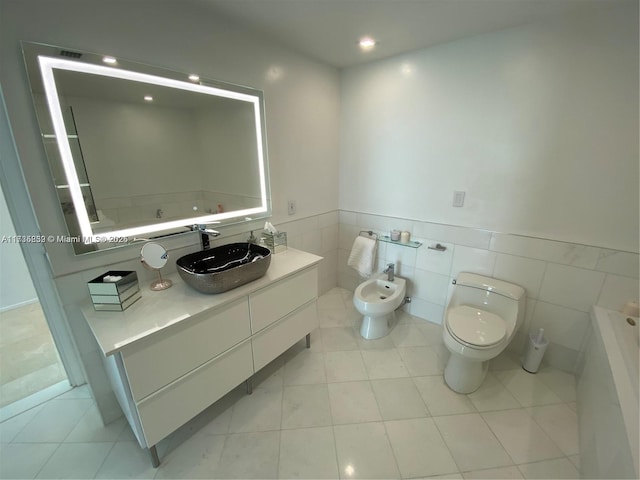 bathroom featuring tile patterned floors, toilet, tile walls, a bidet, and vanity