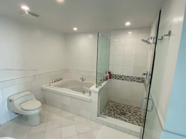 bathroom with tile patterned flooring, tile walls, toilet, and separate shower and tub