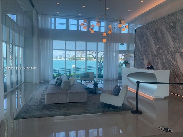 living room featuring a notable chandelier, a towering ceiling, and a water view