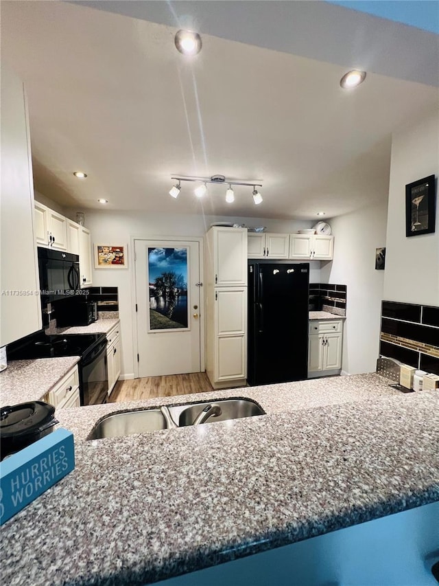 kitchen featuring sink, light hardwood / wood-style flooring, white cabinetry, black appliances, and kitchen peninsula