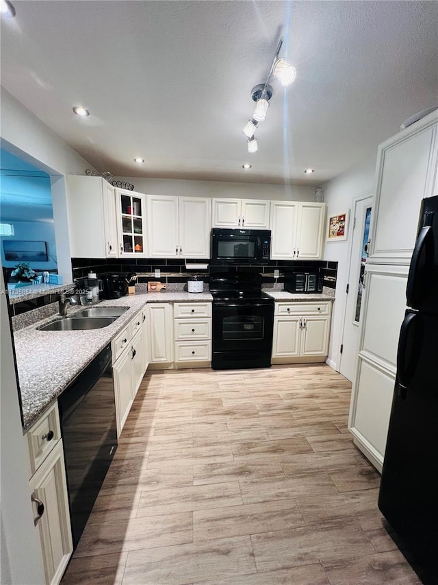 kitchen featuring sink, light hardwood / wood-style flooring, white cabinetry, backsplash, and black appliances