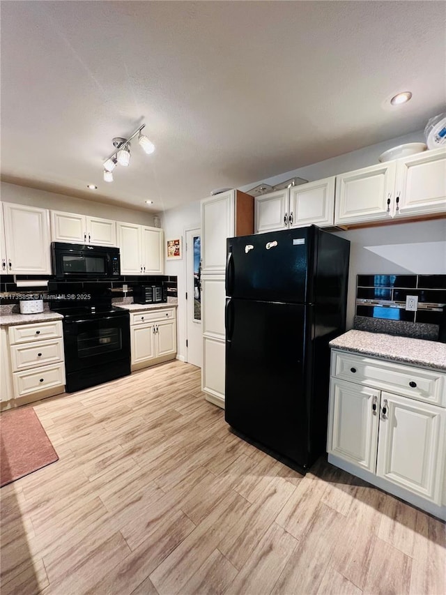 kitchen with light hardwood / wood-style flooring, black appliances, and white cabinets