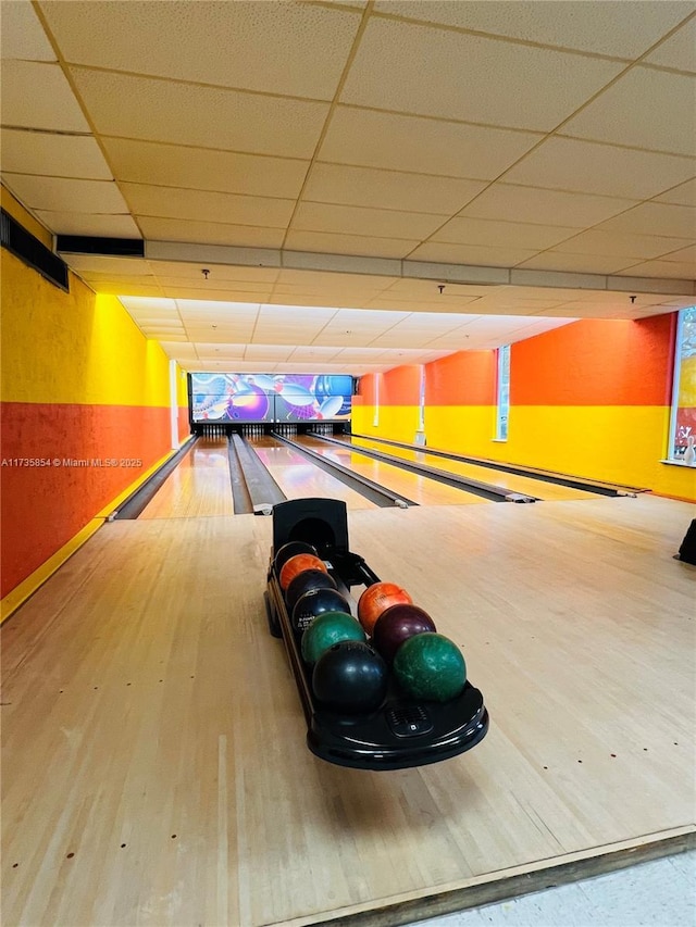 game room with a bowling alley, hardwood / wood-style floors, and a drop ceiling