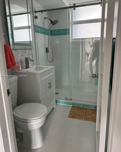 bathroom with vanity, toilet, and a shower with door