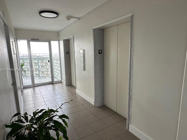 hallway featuring elevator and light tile patterned flooring