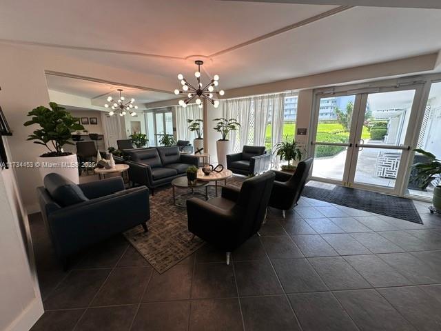 living room featuring dark tile patterned flooring, a chandelier, and french doors