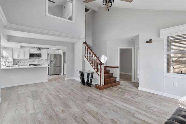 unfurnished living room with ceiling fan, high vaulted ceiling, and light hardwood / wood-style floors