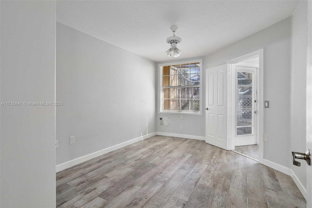 spare room with light hardwood / wood-style flooring and a textured ceiling