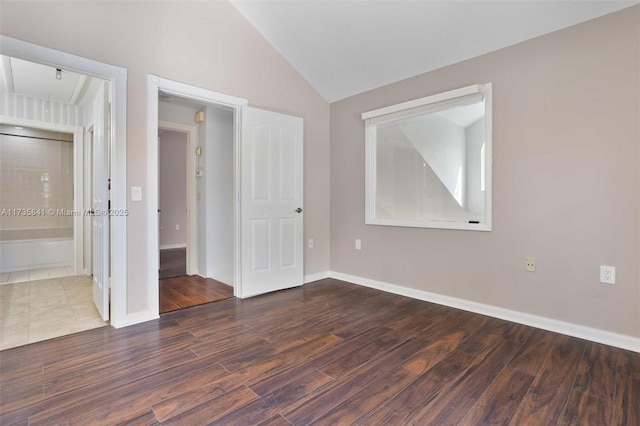 unfurnished bedroom with vaulted ceiling and dark wood-type flooring