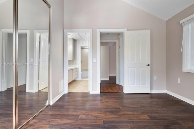 unfurnished bedroom with dark wood-type flooring, vaulted ceiling, and a closet