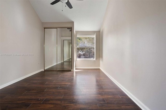 unfurnished bedroom with dark hardwood / wood-style flooring, lofted ceiling, a closet, and ceiling fan