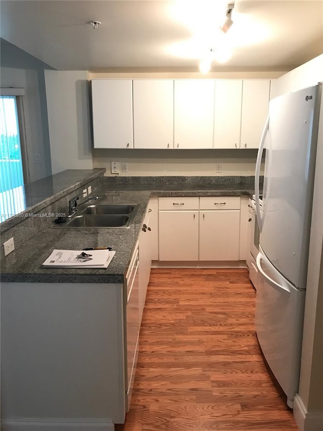 kitchen with white cabinetry, sink, white appliances, and kitchen peninsula