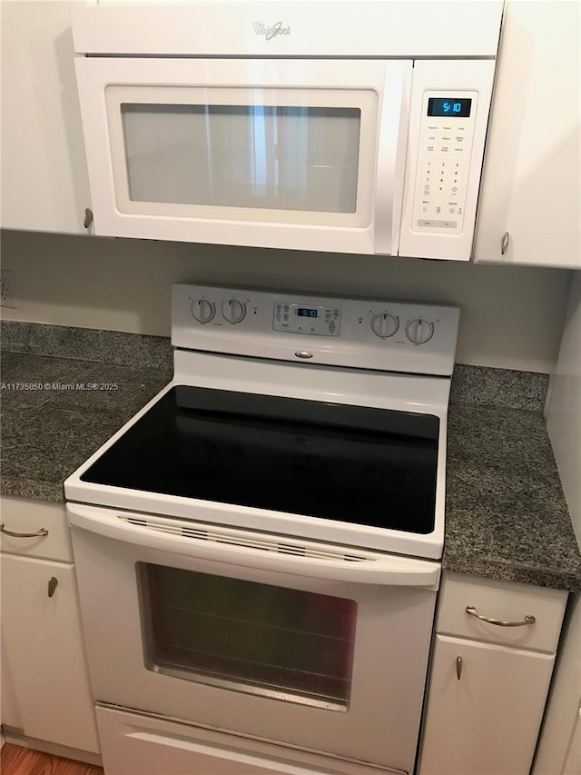 kitchen with white cabinets, white appliances, and dark stone counters