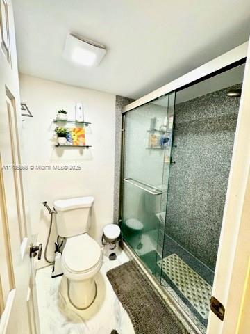 bathroom featuring an enclosed shower and toilet