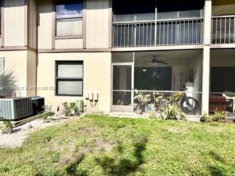 back of property featuring central air condition unit, ceiling fan, and a lawn